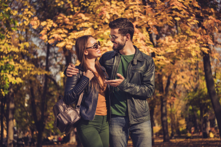 ein lächelnder Mann und eine Frau, die durch den Park gehen