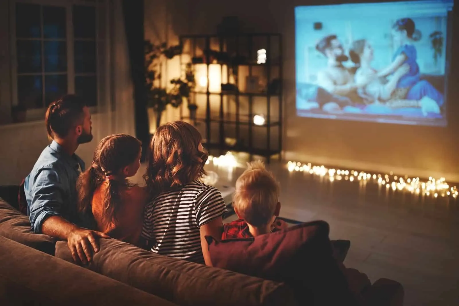 Vater und Mutter mit Kindern Nachts Filme über den Projektor im Wohnzimmer ansehen