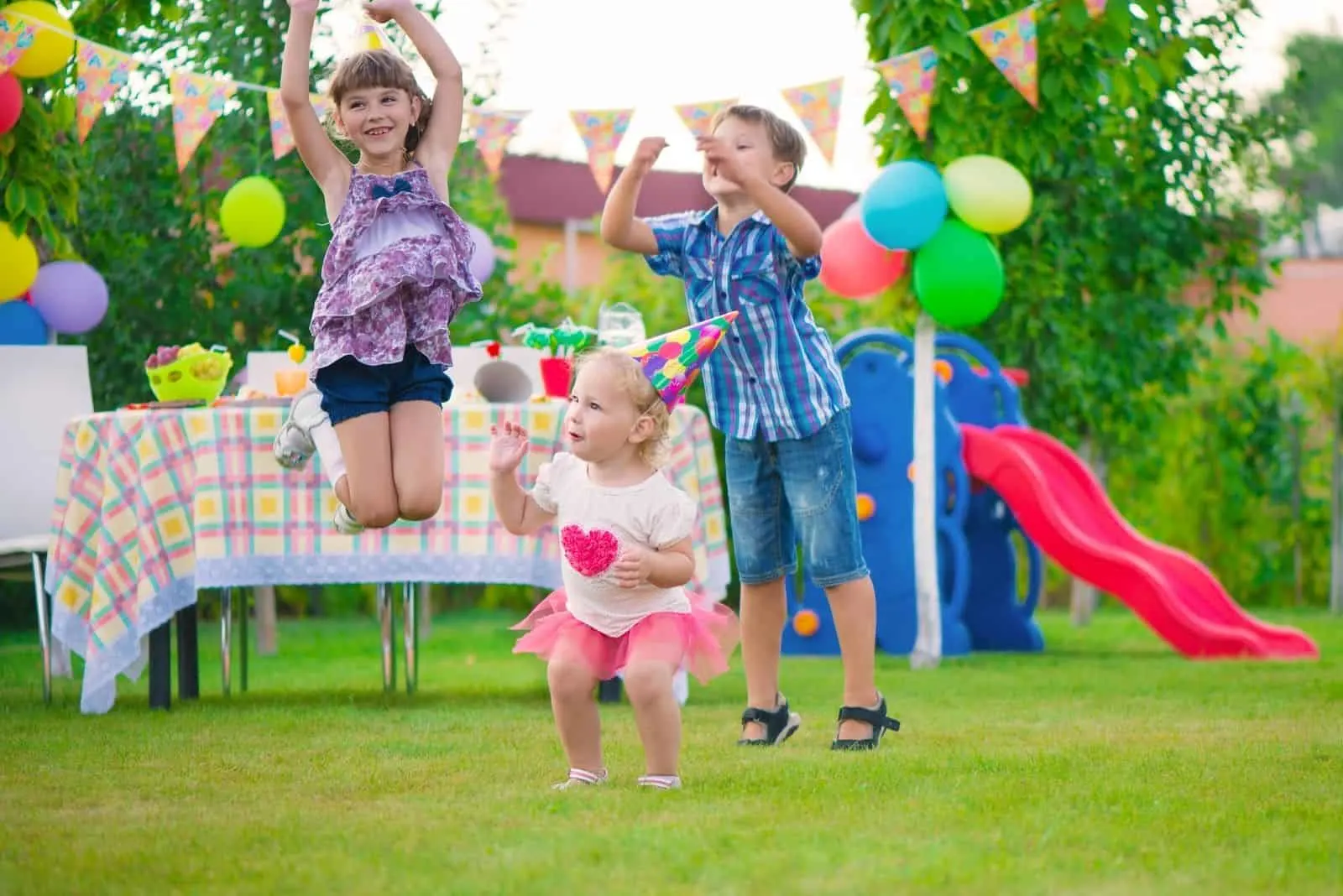 drei Kinder spielen auf der Party im Freien springen