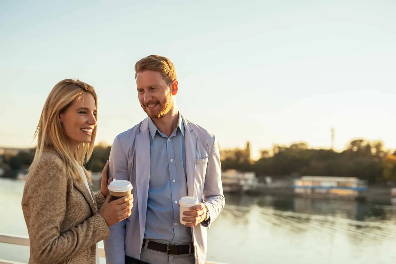 ein Mann und eine Frau stehen mit Kaffee in den Händen und unterhalten sich
