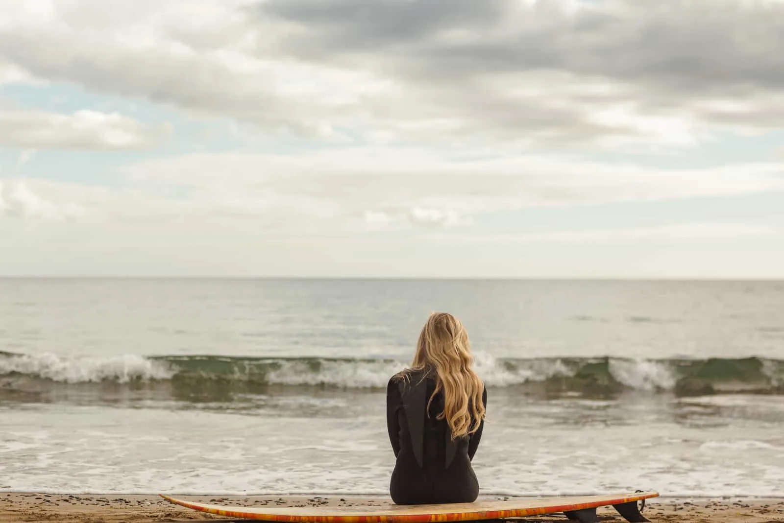 eine Frau mit langen blonden Haaren sitzt am Meer