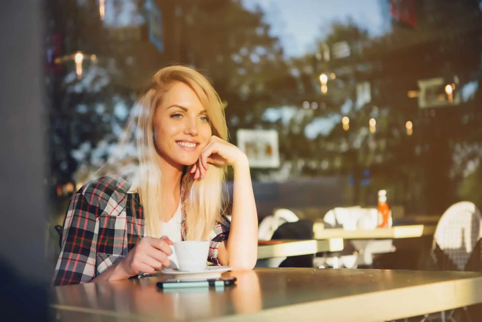 eine lächelnde blonde Frau, die Kaffee trinkt
