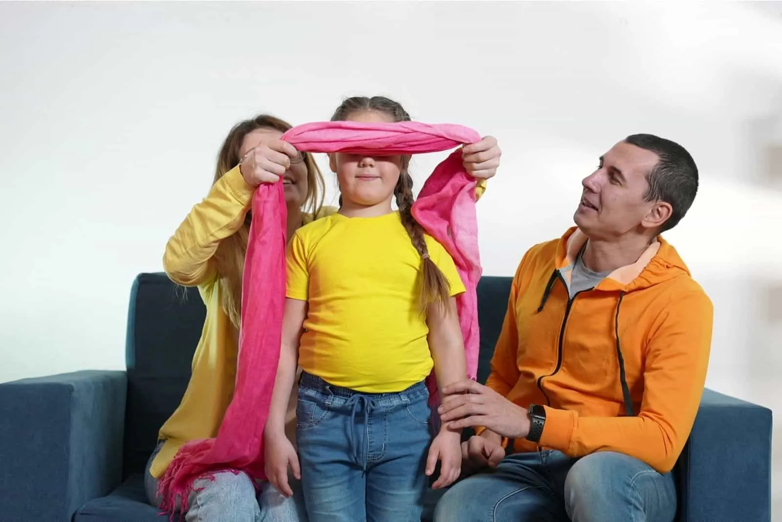 glückliche Familie zu Hause wenn Mama dem Kind eine Augenbinde auflegt