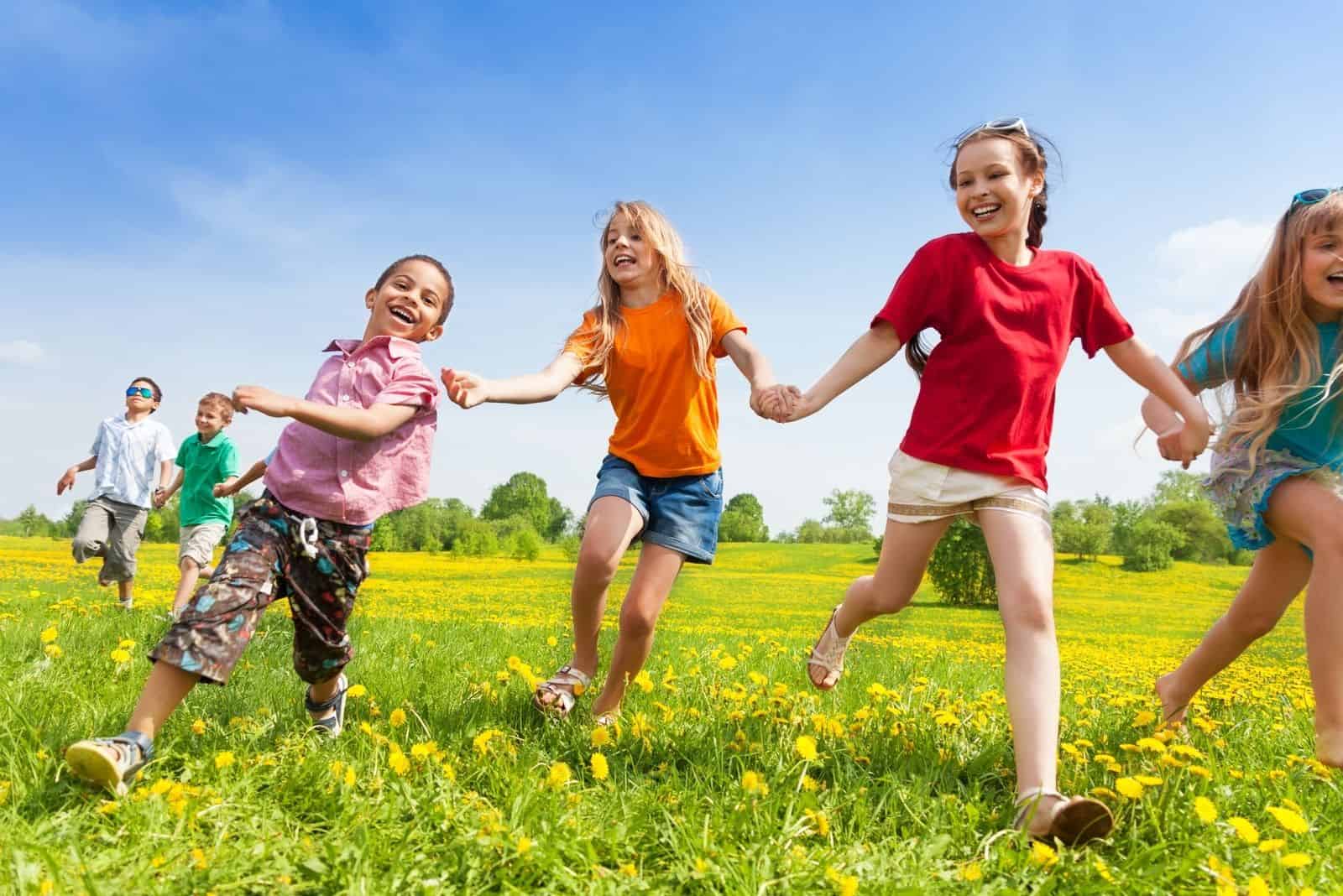 glückliche spielende Kinder Händchenhalten im Freien und Laufen