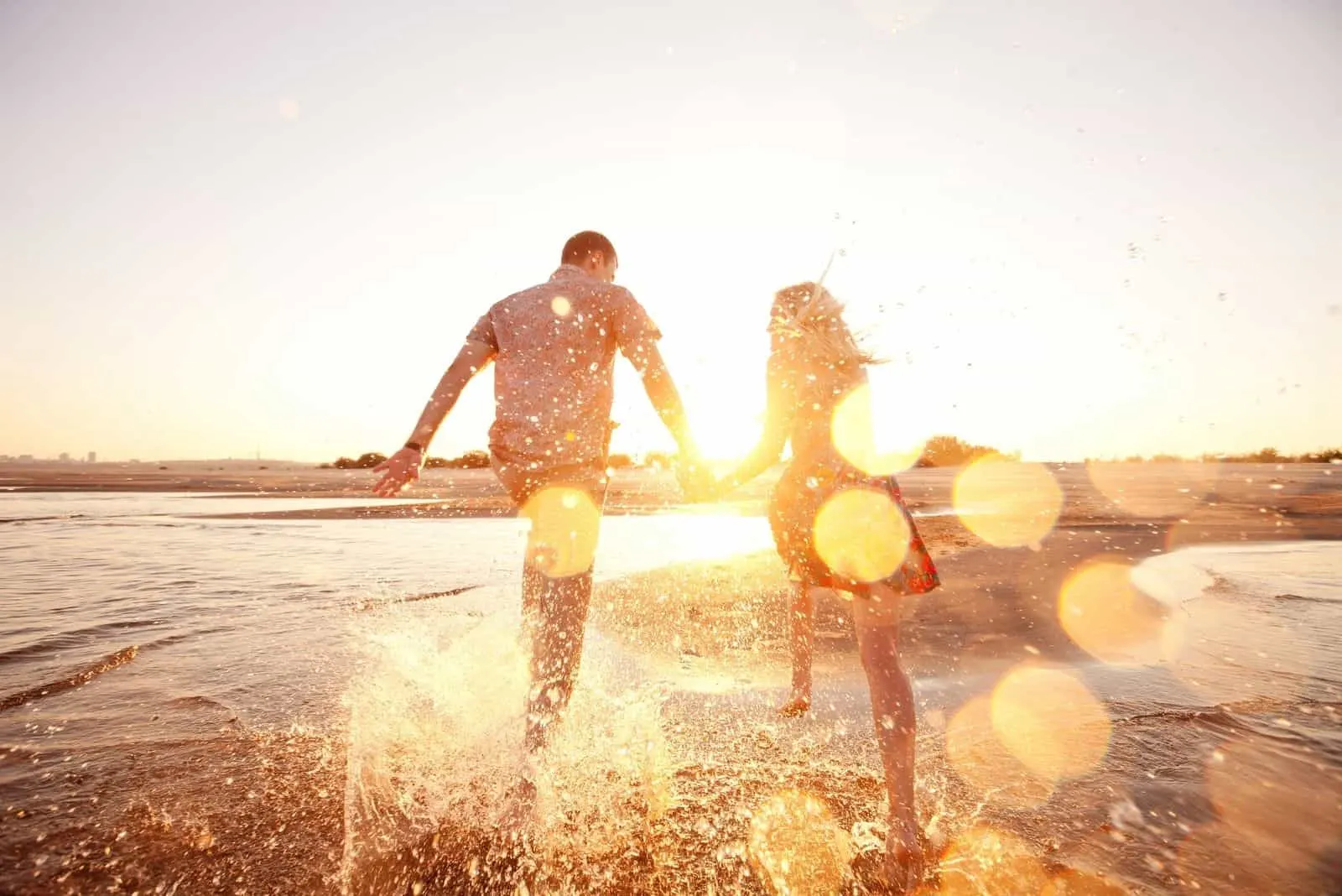 glückliches Paar läuft am Strand mit Blick auf die Sonne