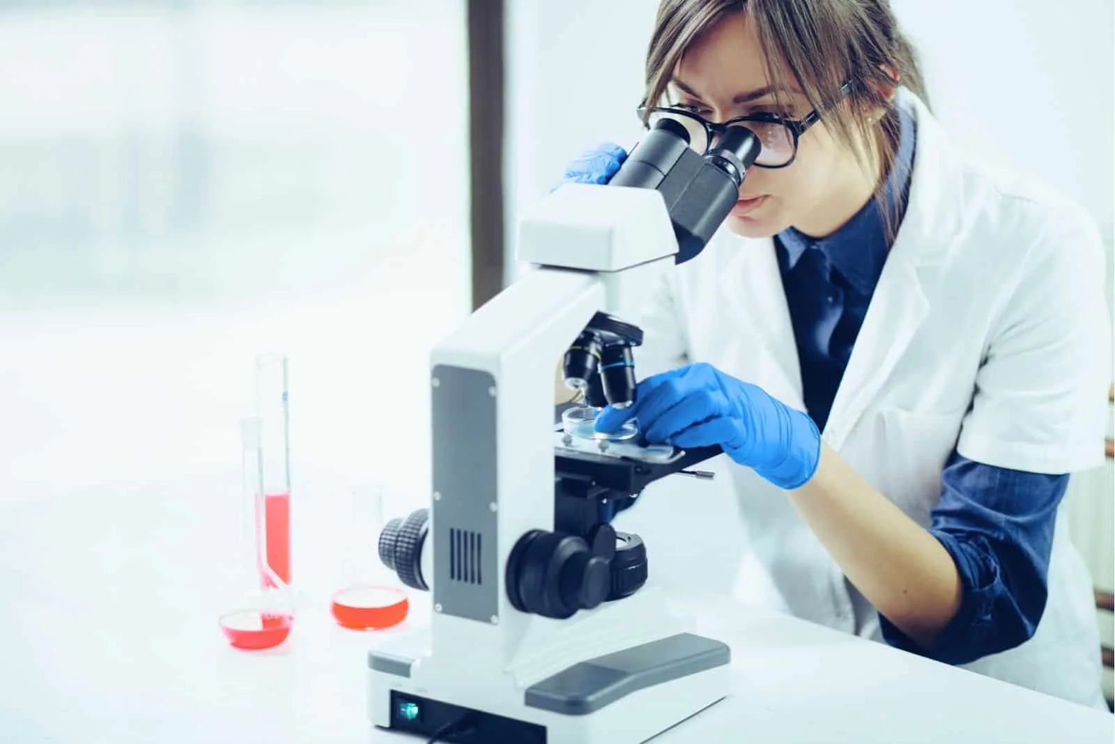 junge Wissenschaftlerin Blick durch ein Mikroskop im Labor