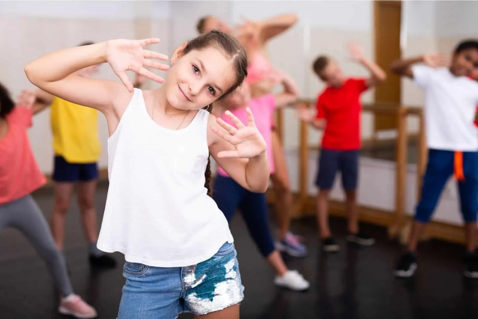 sportliches 10-jähriges Mädchen Übungsbewegungen von kräftigem Tanz während des Gruppenunterrichts in der Tanzschule