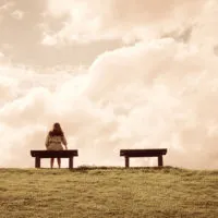 Frau sitzt allein auf einer Bank