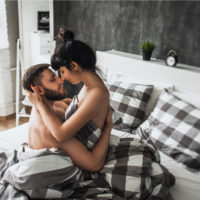 ein Mann und eine Frau, die sich halbnackt im Bett küssen