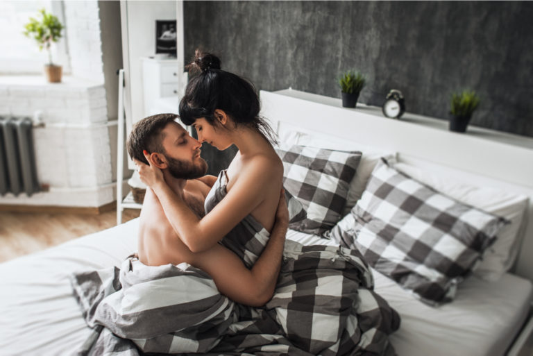 ein Mann und eine Frau, die sich halbnackt im Bett küssen