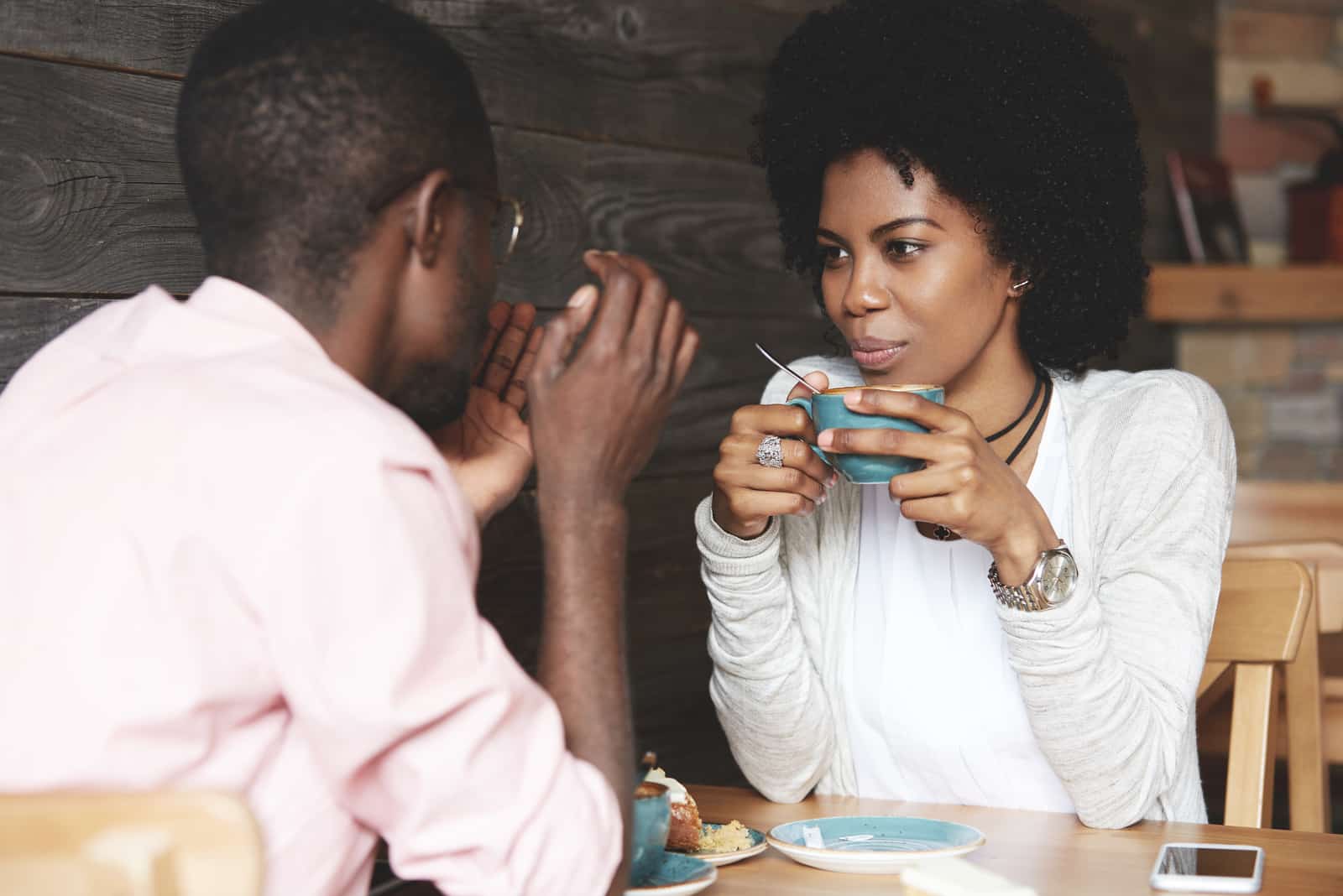 Frau, die eine Tasse Kaffee hält, zuhört und ihren Freund ansieht