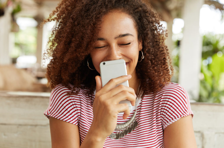 Frau, die ein Telefon hält und lacht