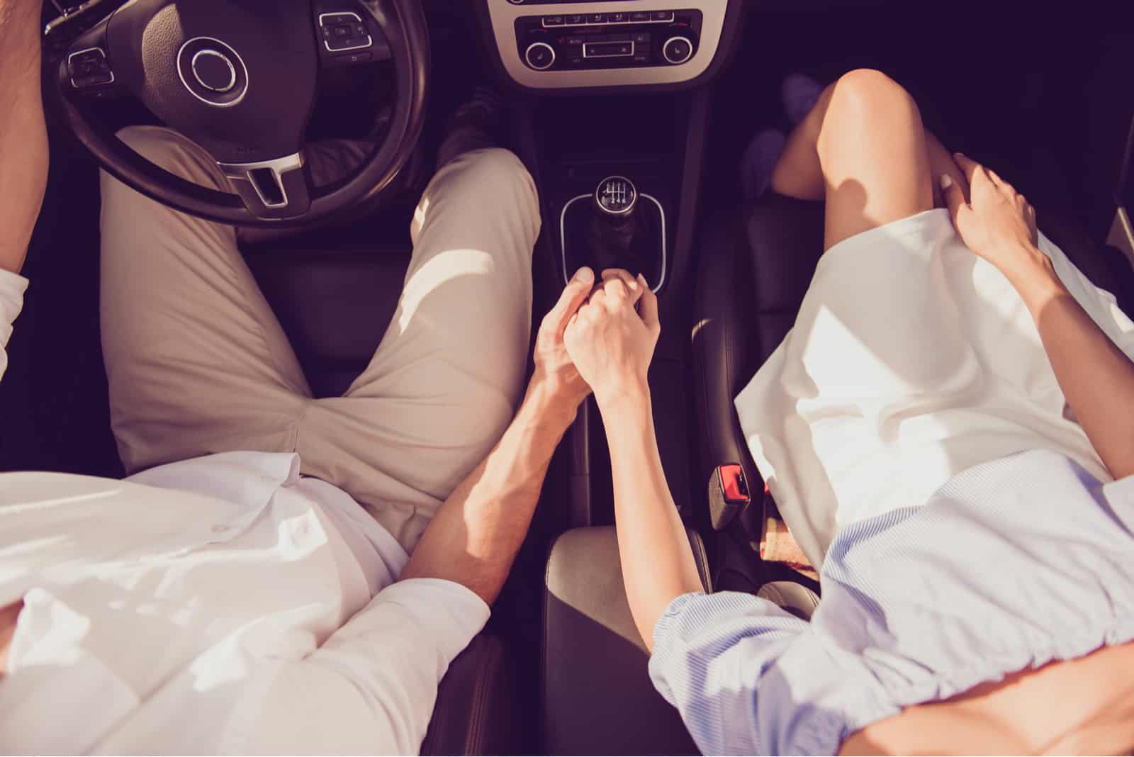 Romantisches Paar im Auto, das Händchen hält