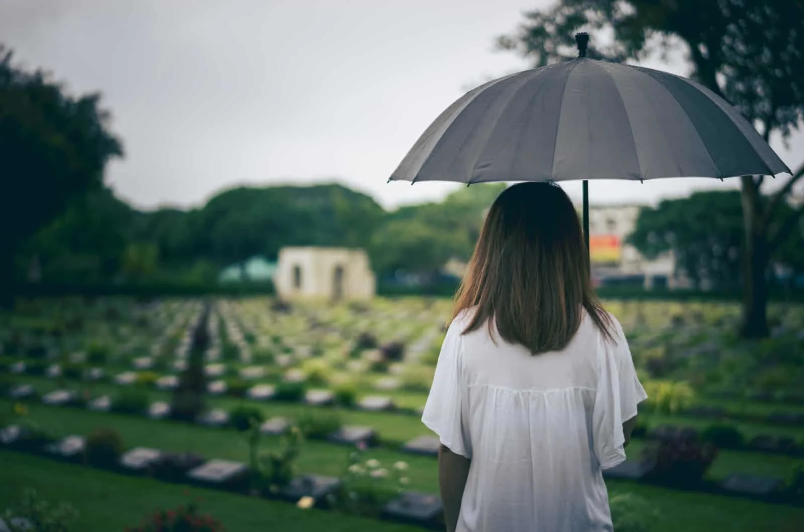 Frau mit Regenschirm am Friedhof
