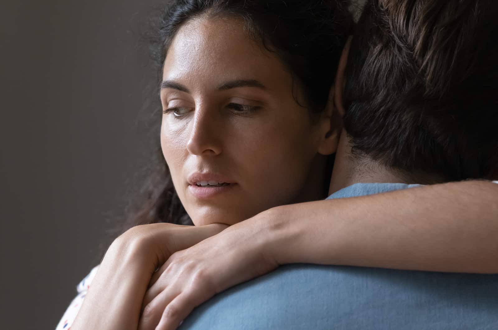 Frau umarmt ihren Partner mit traurigem Gesichtsausdruck