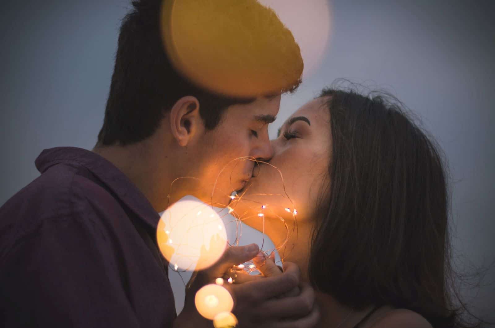 Paar küssen sich mit Lichtern um sie herum