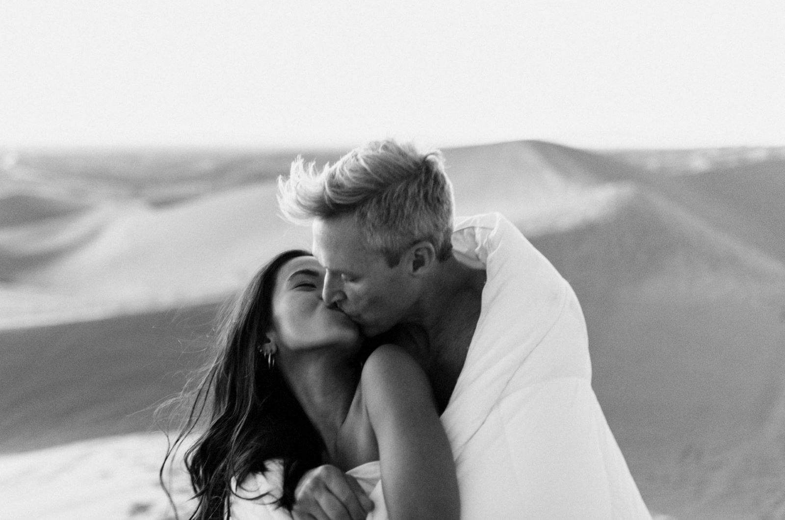 Schwarz-Weiß-Foto eines Paares, das sich in der Wüste küsst