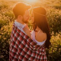 Zwei Menschen küssen sich bei Sonnenuntergang auf einem Feld