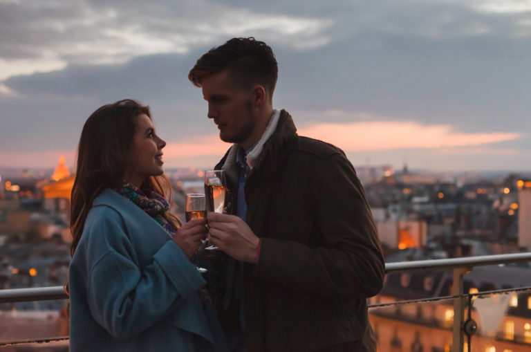 Mann und Frau auf einem Balkon mit Gläsern Champagner