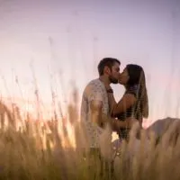 Paar küsst sich in einem Feld mit lila Himmel