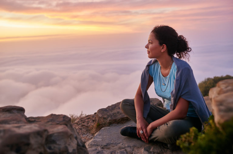 Frau auf einer Klippe, die den Himmel beobachtet