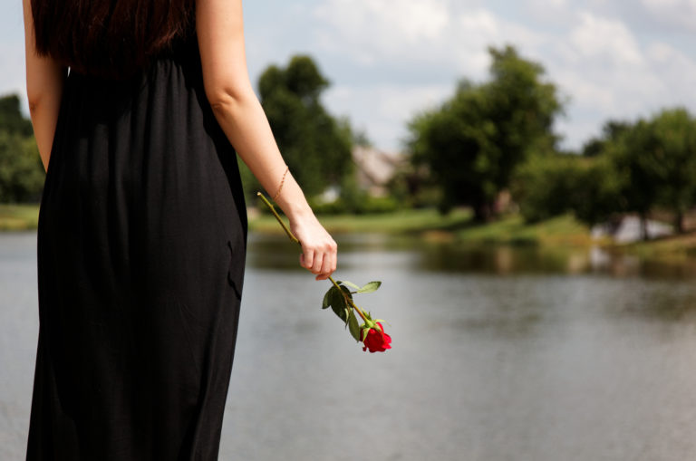 Frau im schwarzen Kleid mit Rose