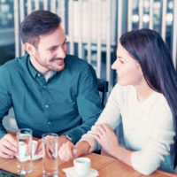 Ein lächelnder Mann und eine Frau sitzen an einem Tisch und unterhalten sich