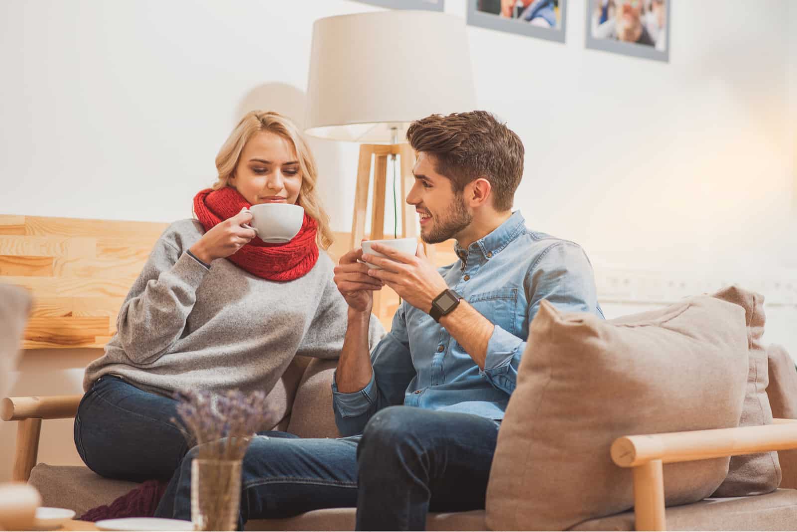 ein Mann und eine Frau sitzen auf der Couch, trinken Kaffee und unterhalten sich