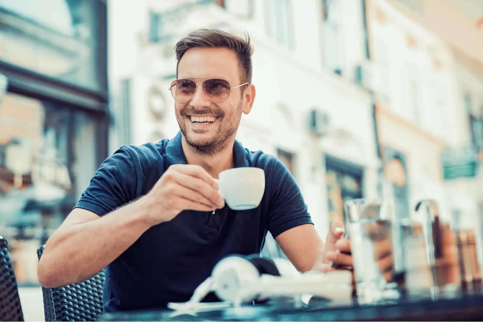 ein lächelnder mann sitzt an einem tisch und trinkt kaffee