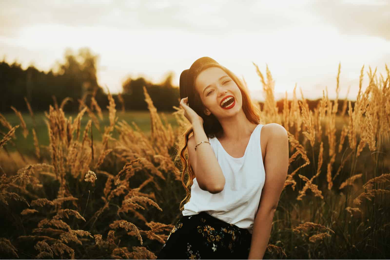 eine lächelnde Frau steht auf einem Weizenfeld