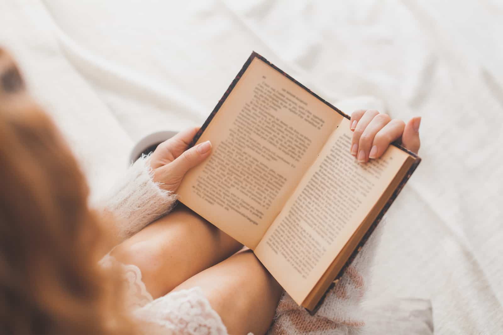 Frau sitzt auf dem Bett und liest ein Buch