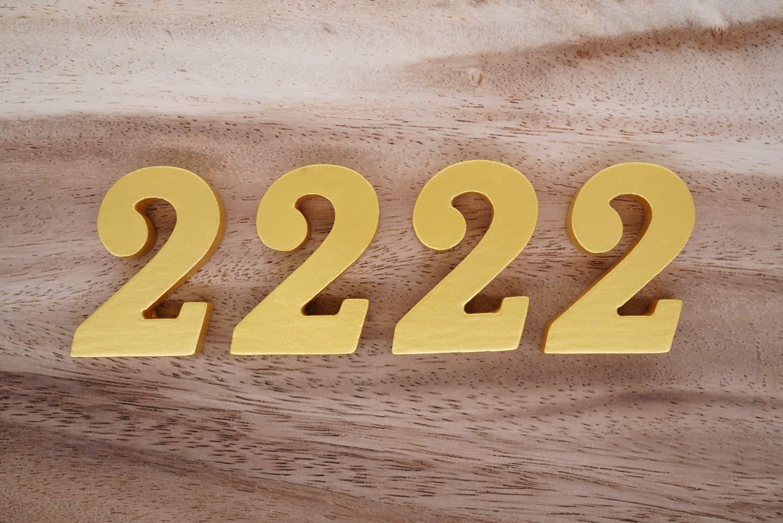 goldene Zahl 2222 auf Holzhintergrund