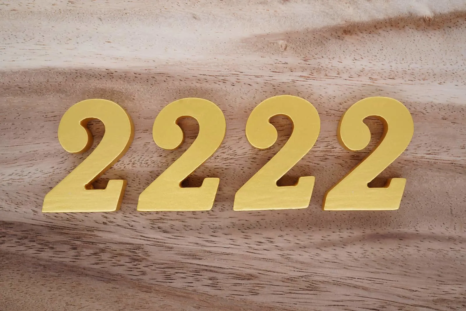goldene Zahl 2222 auf Holzhintergrund