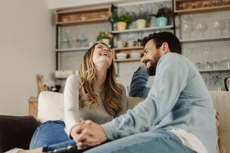 Paar sitzt lachend auf dem Sofa