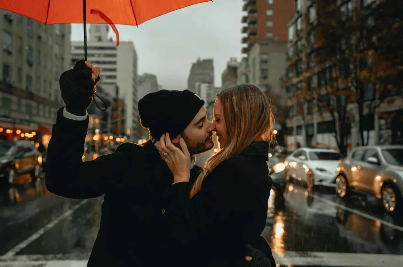 Paar küssen sich, während Mann einen Regenschirm hält