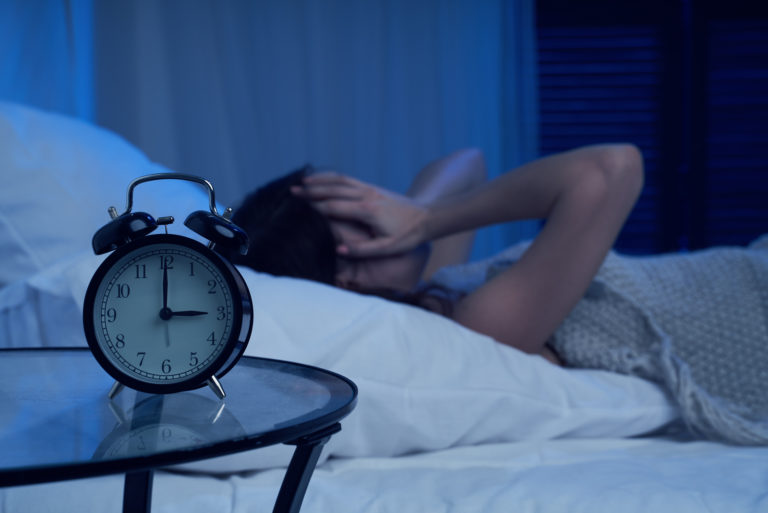 Die Frau liegt im Bett und hält ihren Kopf