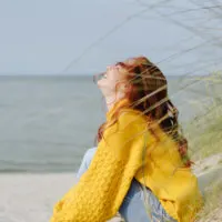 glückliches Mädchen, das am Strand sitzt