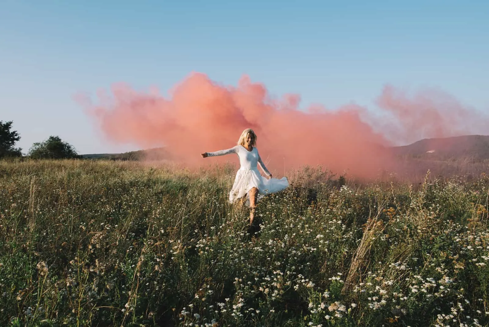 Braut auf dem Feld mit rosa Rauch