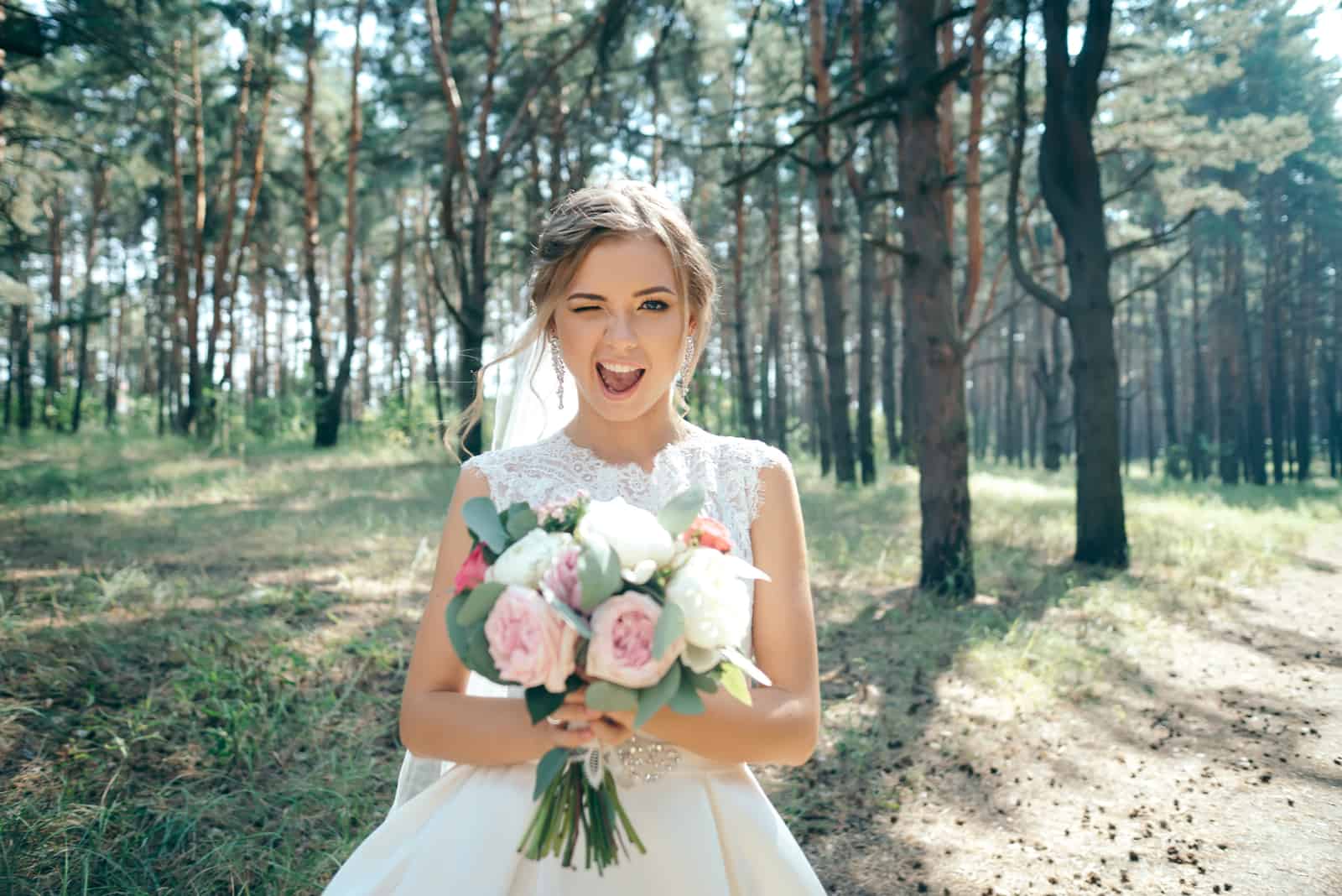 Braut mit Blumenstrauß zwinkernd