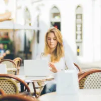 Frau im weißen Hemd, die draußen im Café arbeitet