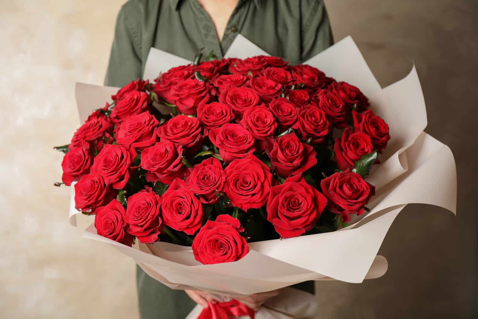 Frau hält luxuriösen Blumenstrauß aus frischen roten Rosen