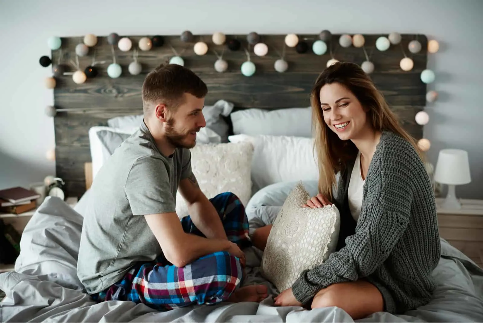 Junge Paare, die auf dem Bett in den Pyjamas sprechen