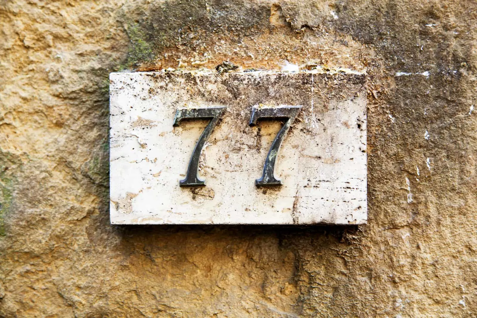 alte Hausnummer 77 an der Wand