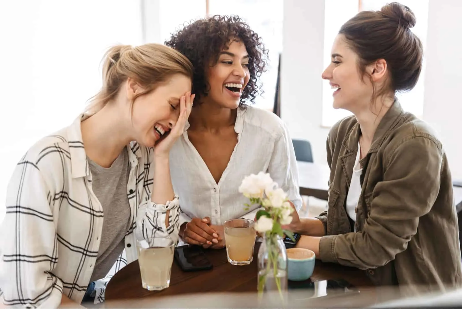 drei Freunde lächelnd in einem Café beim Kaffeetrinken