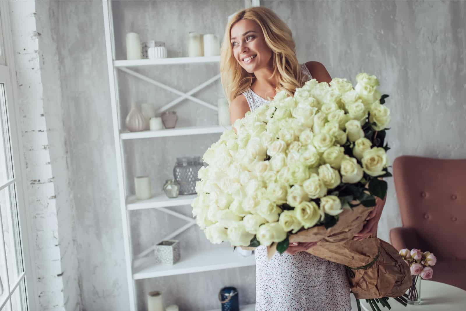 glückliche Frau mit großem Strauß weißer Rosen