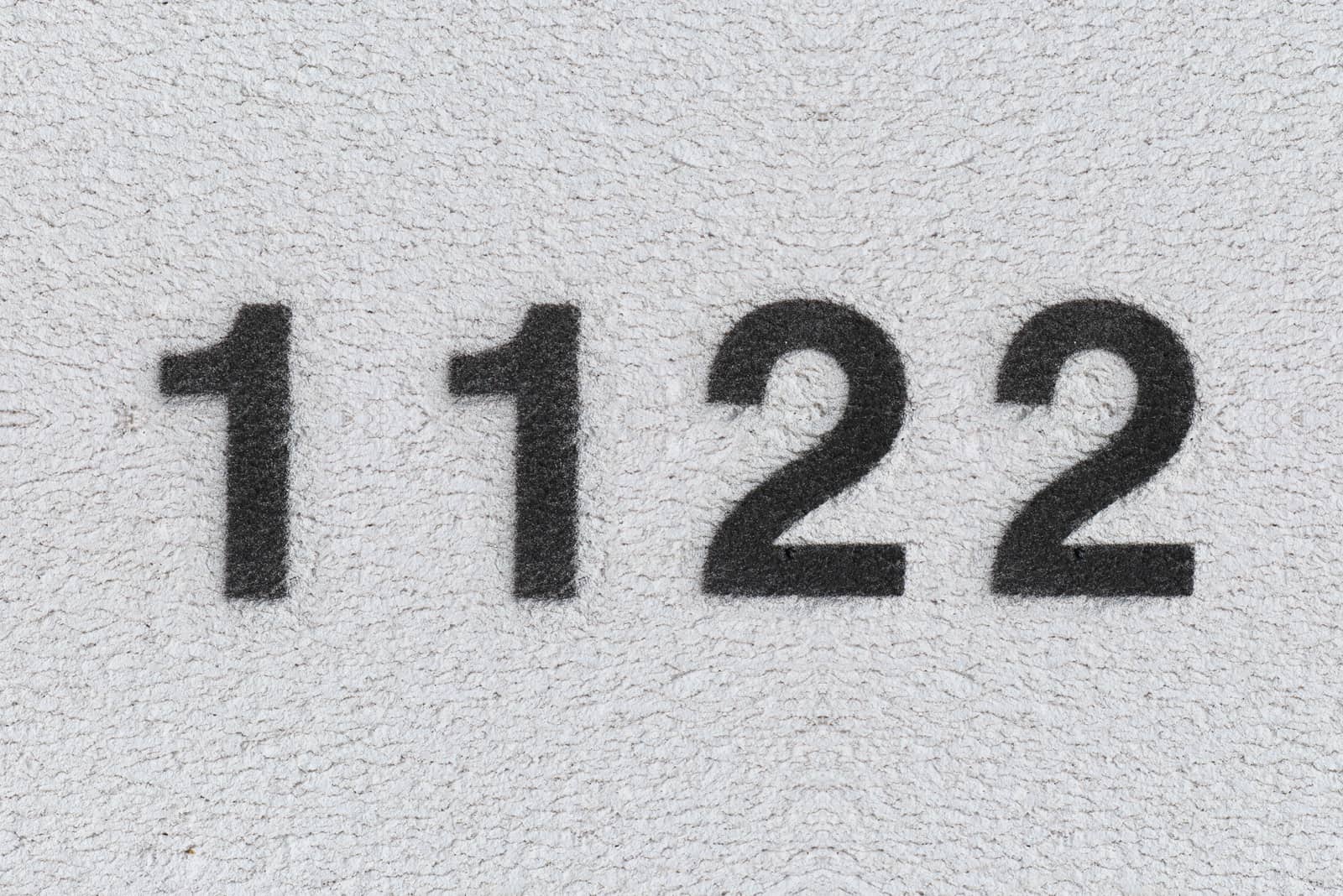 schwarze Nummer 1122 auf grauer Wand