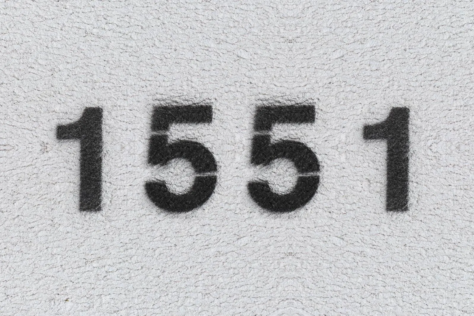 schwarze Nummer 1551 auf grauer Wand