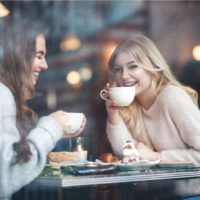 Lächelnde Freunde sitzen in einem Café und trinken Kaffee