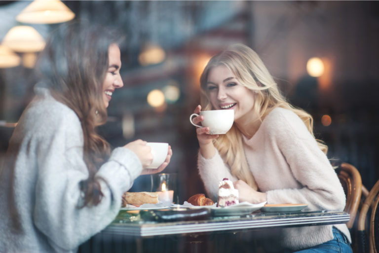 Lächelnde Freunde sitzen in einem Café und trinken Kaffee