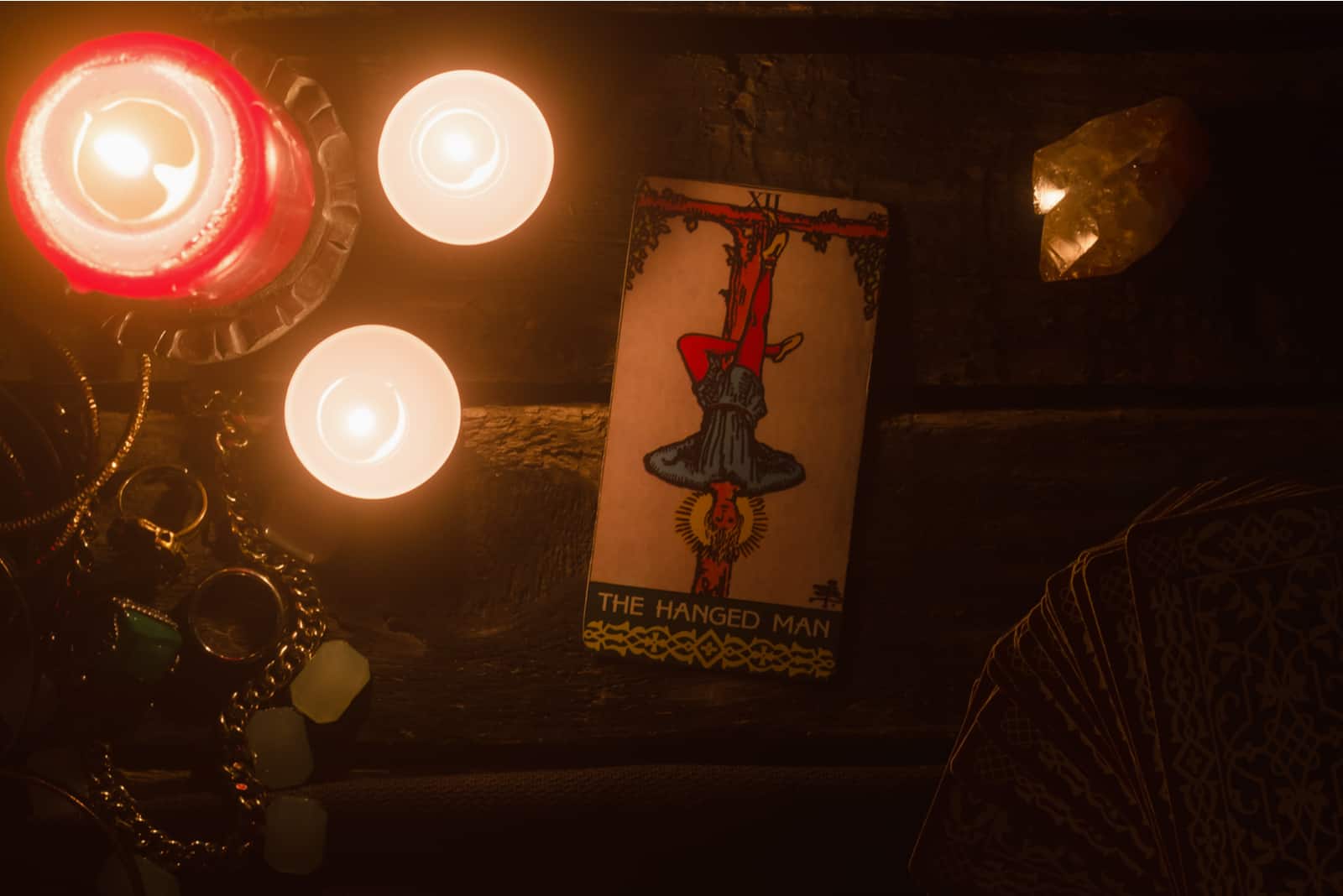 Die Tarotkarte des Gehängten auf dem Tisch mit Kerzen